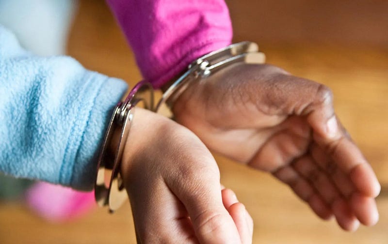 Image of an African American child’s hands in handcuffs
