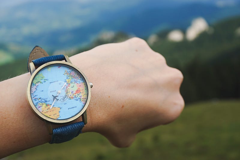 Closeup shot of a watch tied to a hand with world map on it