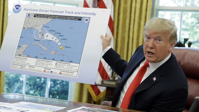 President Trump in the Oval Office, holding up a map of Hurricane Dorian produced by NOAA. A black line is added to the map.