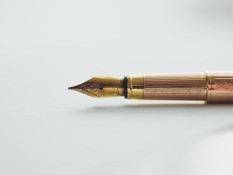 Golden ink pen on white background Becka Lynn