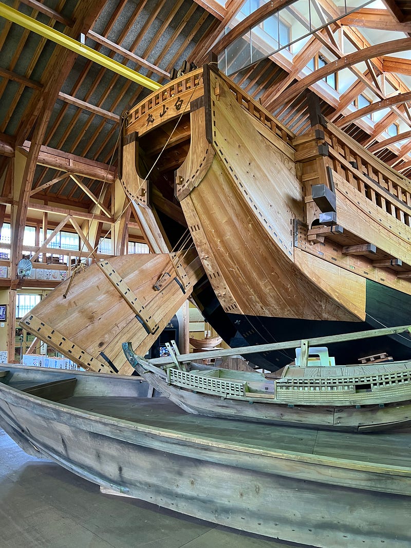 The back of a huge wooden sailing ship inside a converted school auditorium in Shukunegi, Sado Island.
