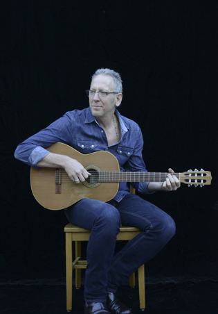 Darden Smith sitting on stool with guitar