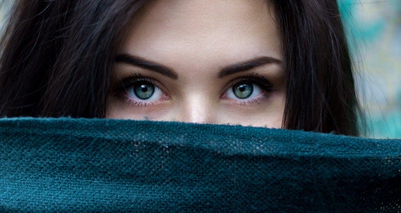 Green-eyed dark-haired woman veiled behind scarf. Becka Lynn