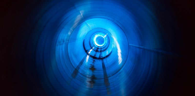 Abstract image of a tunnel or conduit with light at the center, representing a pipeline carrying structured work toward a defined outcome.