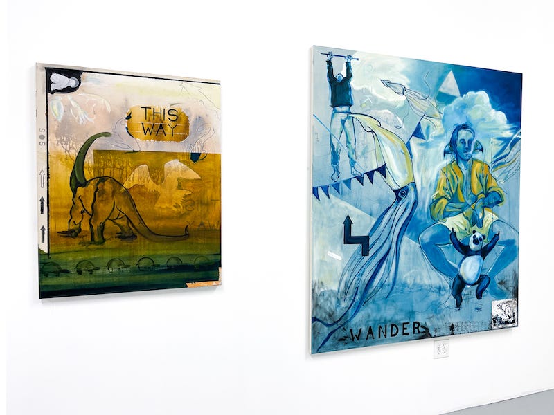 Two paintings are shown by Colin Fleck. The left painting has a prominent depiction of a dinosaur and an inverse shadow of an eagle. The painting is called “Chronostalgia.” To the right of it is a large-scale painting, that depicts a shaman against a background of blue. There are shrimp, text, and clouds visible on the canvas. The title of the piece is “Ego Trip: to Dream a Shaman’s Dream.”