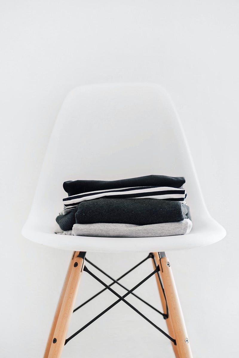 White chair with a neat pile of folded clothes.
