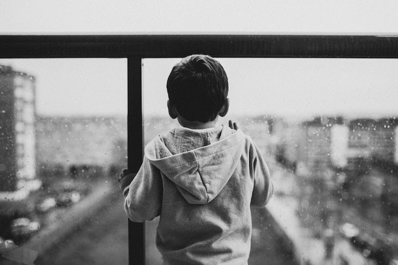 Little boy looking out a window on a rainy day. Black and white. Becka Lynn