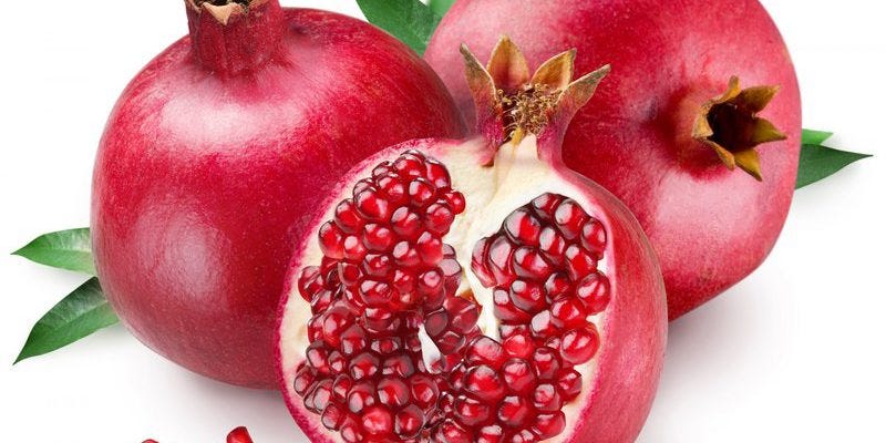 Freshly opened pomegranate with seeds scattered around, highlighting the fruit’s rich color and texture.