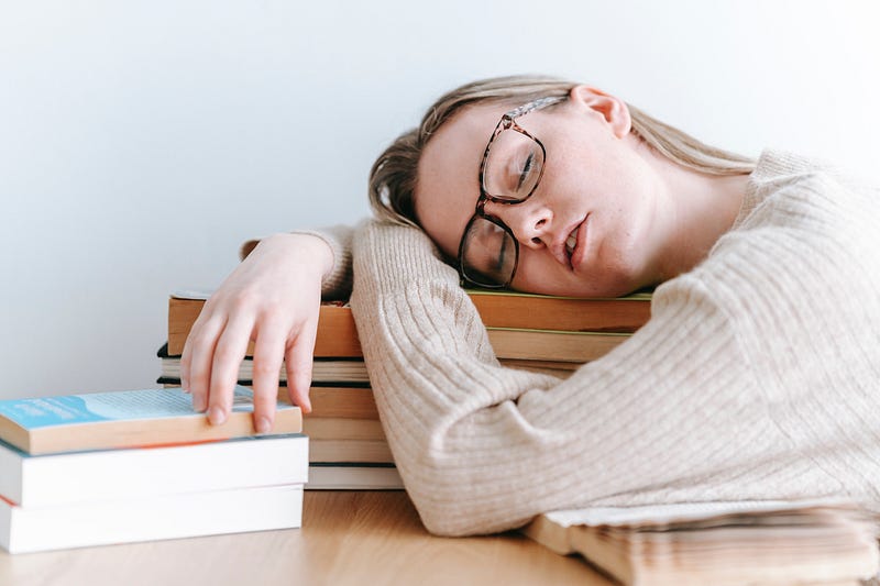 A girl sleeping, resting her head on books.