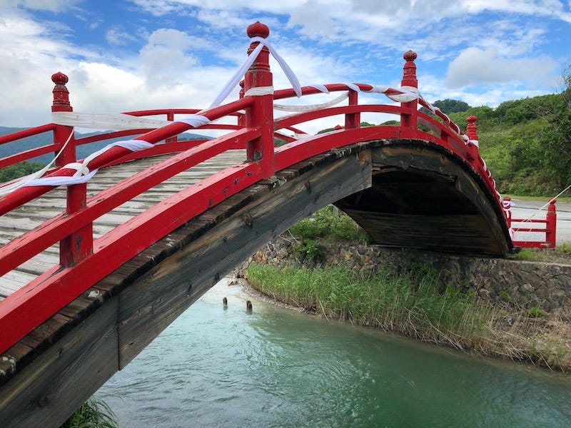 A sacred Japanese bridge spans a stream leading out of Lake Usori at Mt. Osore (Osorezan) in Aomori Prefecture