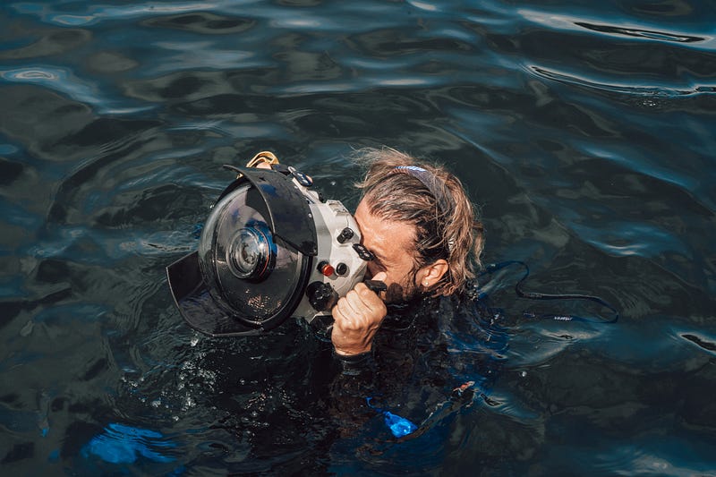 a man in the water looking through a camera