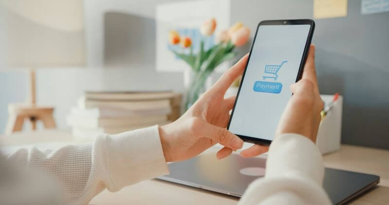 A woman holding a cellphone that shows a landing page of a website.