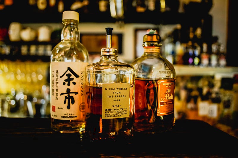 Whiskey bottles lined up on a bar. Drunkenness being normal is, to me, a weird Japanese cultural quirk.