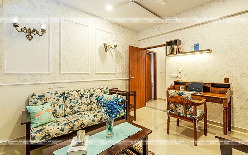 A living room with a blue floral couch and a table.