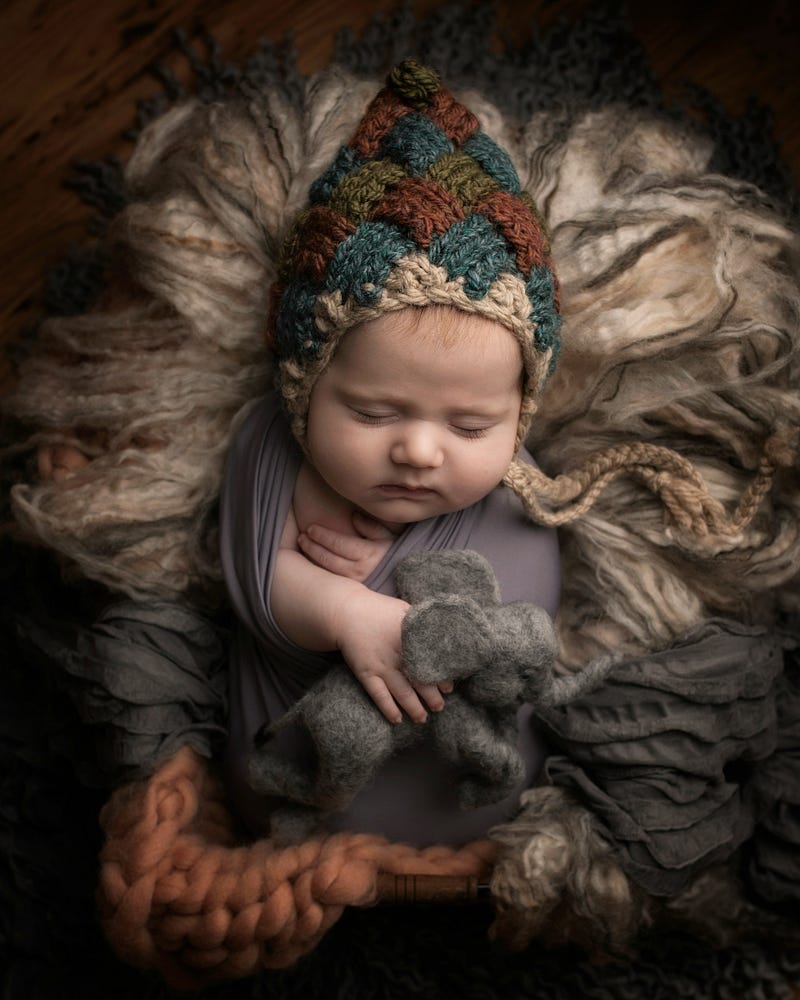 A sleeping baby dressed up like an angel with its hands on her chest
