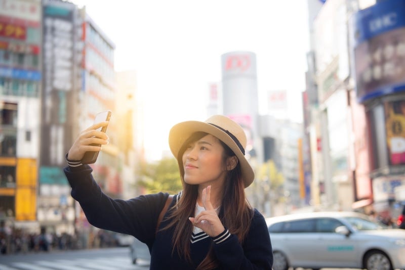 An influencer in Shibuya takes a selfie at the famous Scrable Crossing