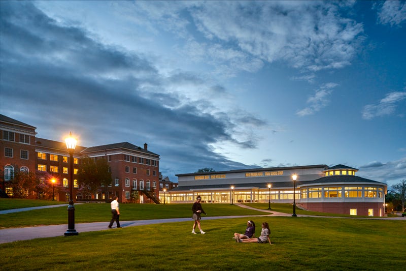 exterior shot of Campus at The Ethel Walker School, showing girls sitting on lawn outside CEntennial Sports Center