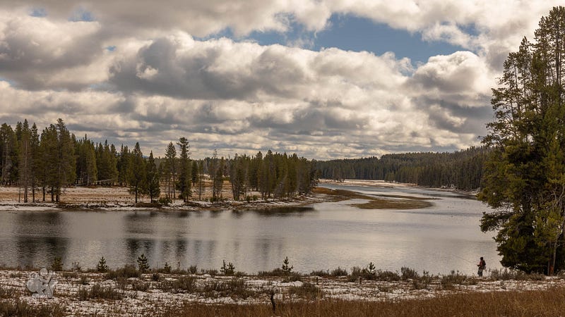 A fisherman walks through the snow down to the Yellowstone River on bright October afternoon. A fisherman walks through the snow down to the Yellowstone River on bright October afternoon.