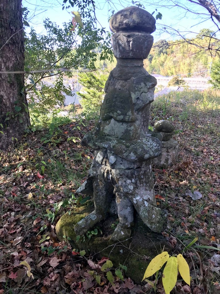 Repaired Buddhist statue stands among fallen leaves.
