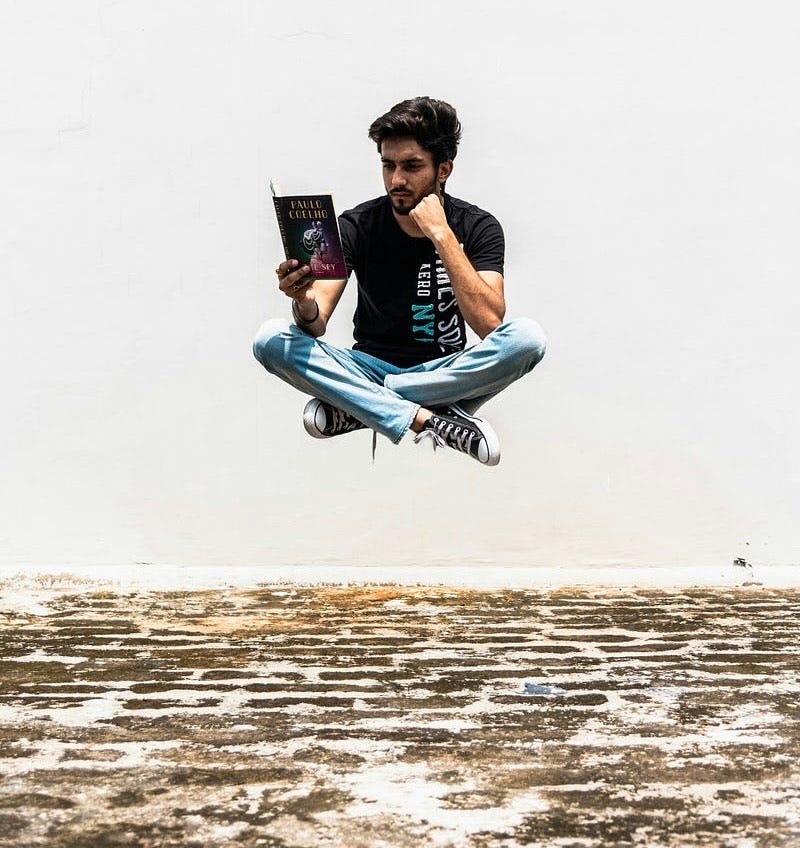A young man reading a book, levitating off the ground