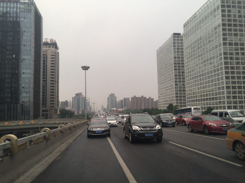image of a busy street--traffic heading in one direction with buildings on the right and left side