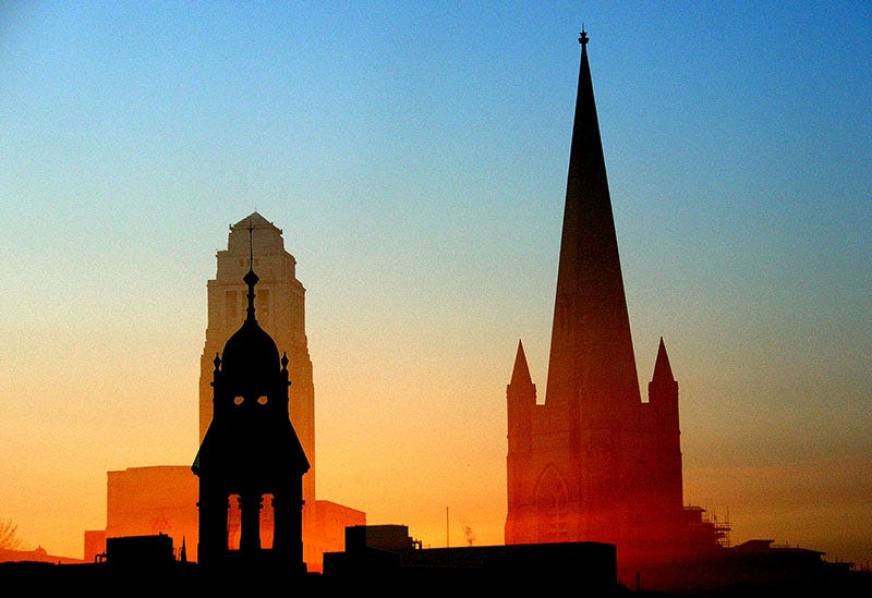 A sunset view of Leeds University campus featuring Clothworkers Concert Hall, Parkinson Building clock tower and the Emmanuel Centre spire.