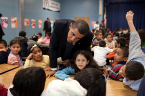 A photo of Barack Obama visiting a classroom full of students. 