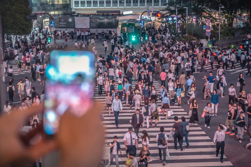 A tourist takes a photo of Shibuya’s iconic Scramble Crossing in Japan with their cellphone