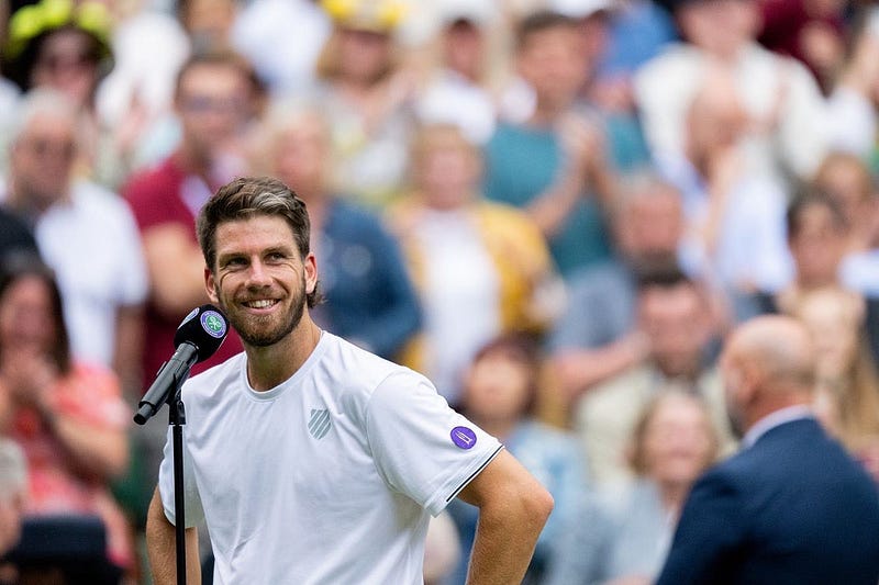Cam Norrie smiling at microphone with Illuvium logo on arm.