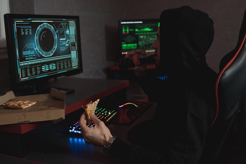 Man in Black Hoodie Eating His Snack in Front of the Computer