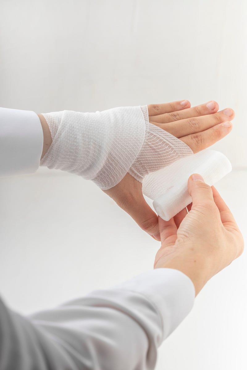 Someone wrapping a hand with gauze.