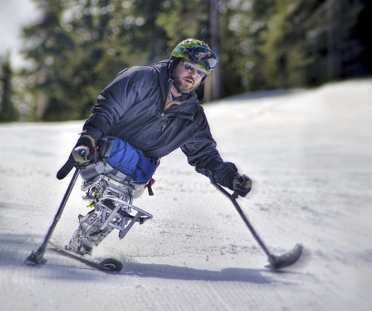 Man without legs using specialized equipment to help him ski as an alternative PTSD treatment