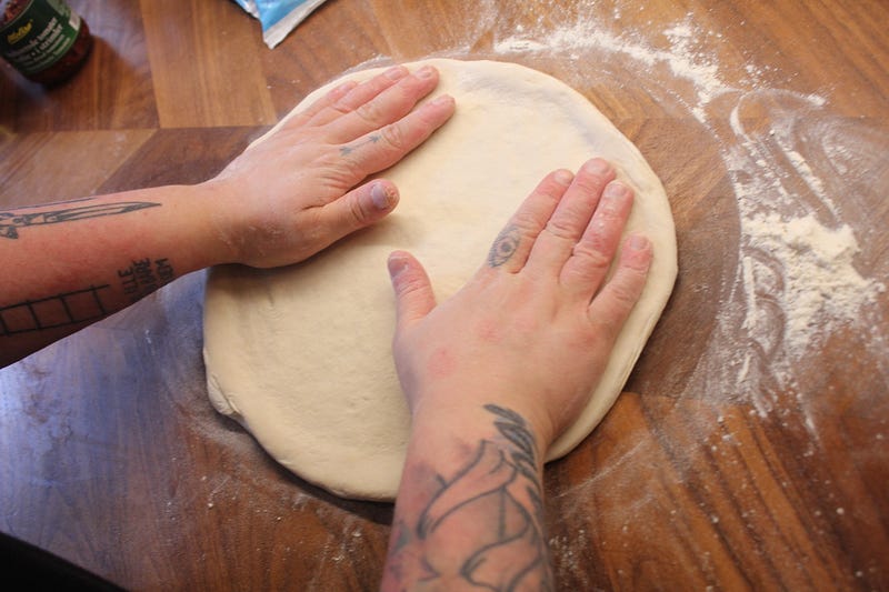 A person kneading a pizza dough