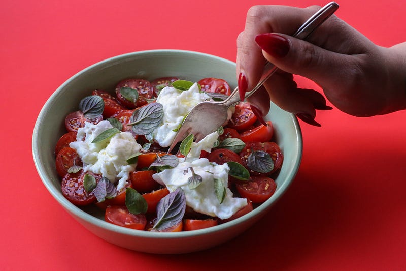 Tomato salad with mozzarella and mint on a red background