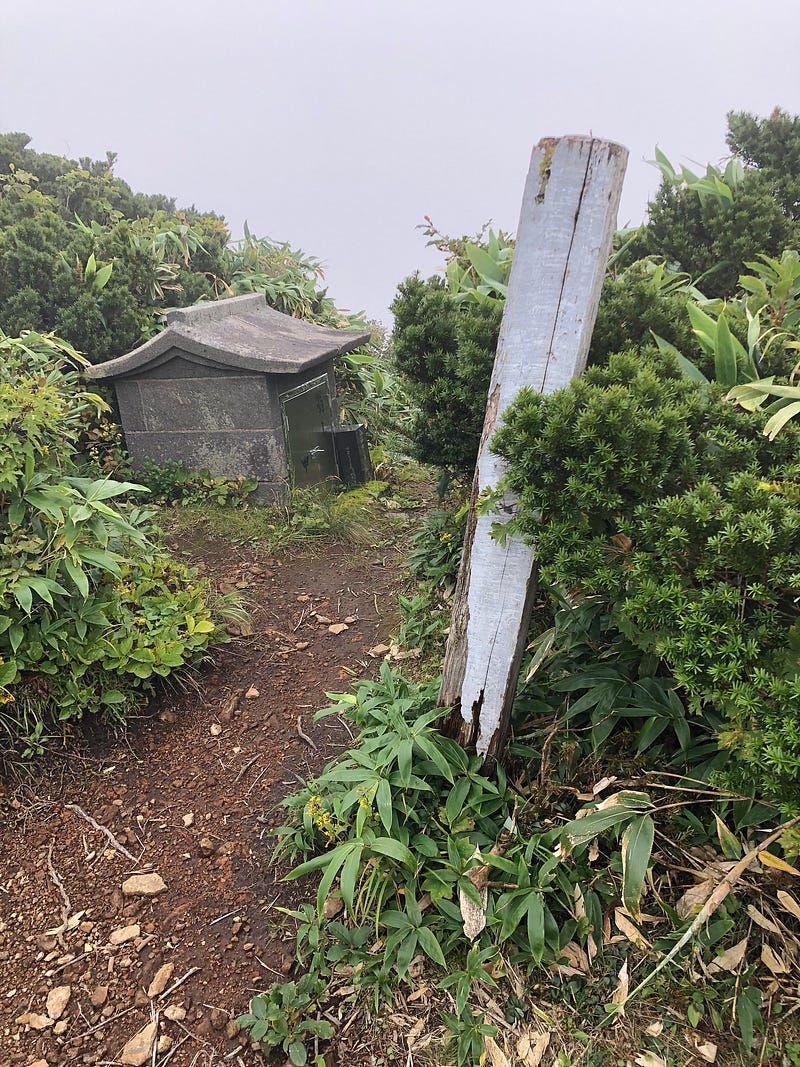 A small concrete shrine amongst the clouds at the summit of Okina-san