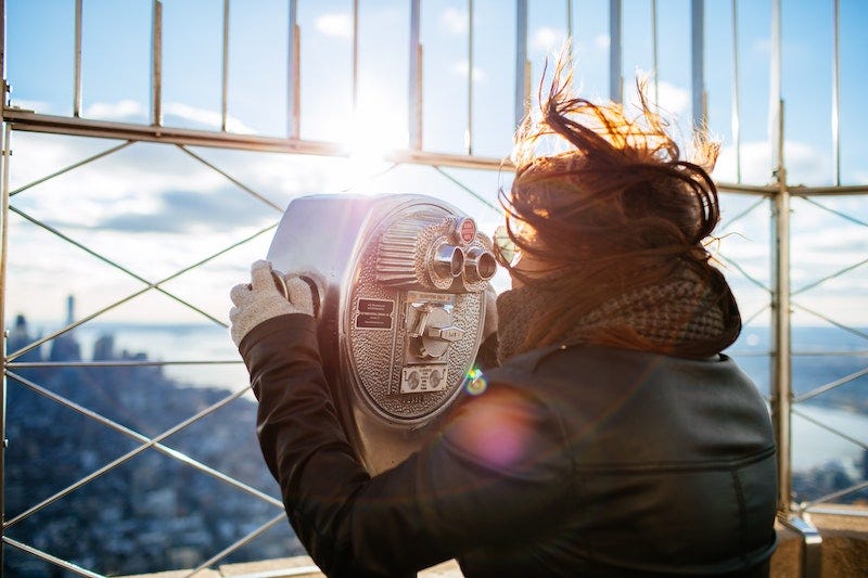 Woman using coin binoculars at the Empire State Building in New York City.