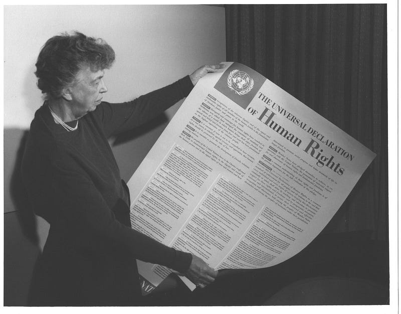 Black and white picture of Eleanor Roosevelt, an elderly white woman, holding up a large copy of the Universal Delcaration of Human Rights