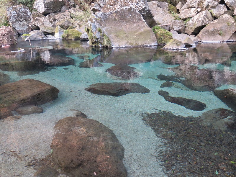 Aqua clear water in a stream with boulders.