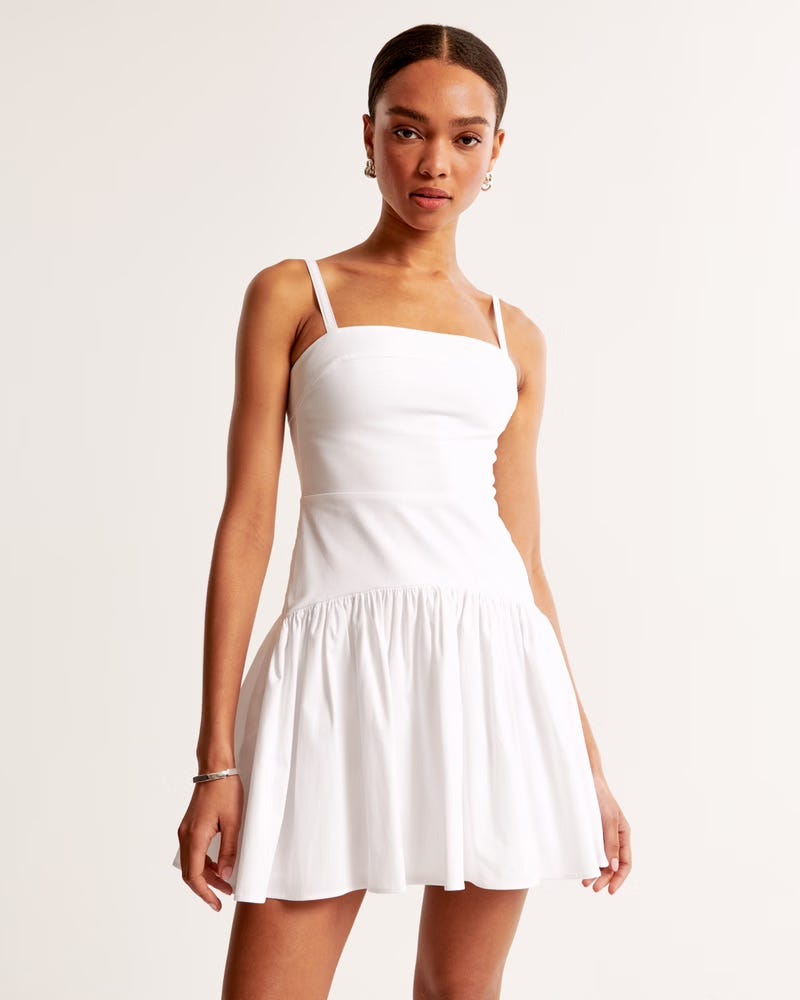 Model wearing a white, short sundress.