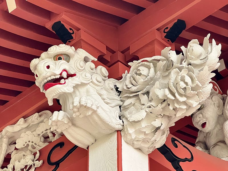 Carving of lion and flowering plants under the roof of the Tenchikon Shrine, Mount Haguro.