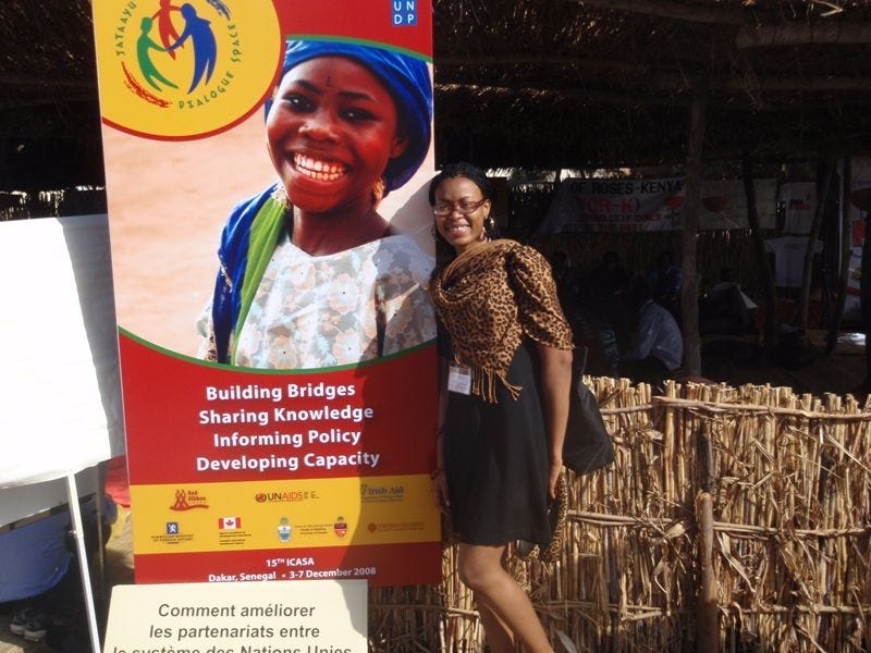 Dr Juliet Iwelunmor stands beside a banner for public health