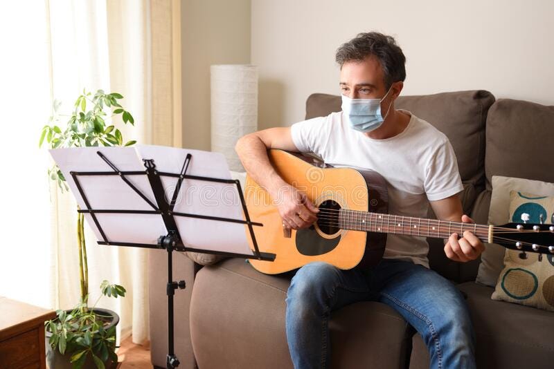 A goofy stock image of a man in a mask learning guitar