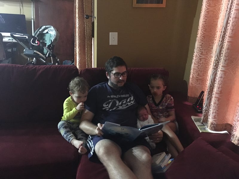 father reads with kids on couch