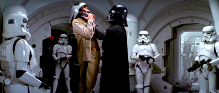 A screenshot from Star Wars showing Darth Vader with storm troopers. Vader is intimidating one of the troopers.