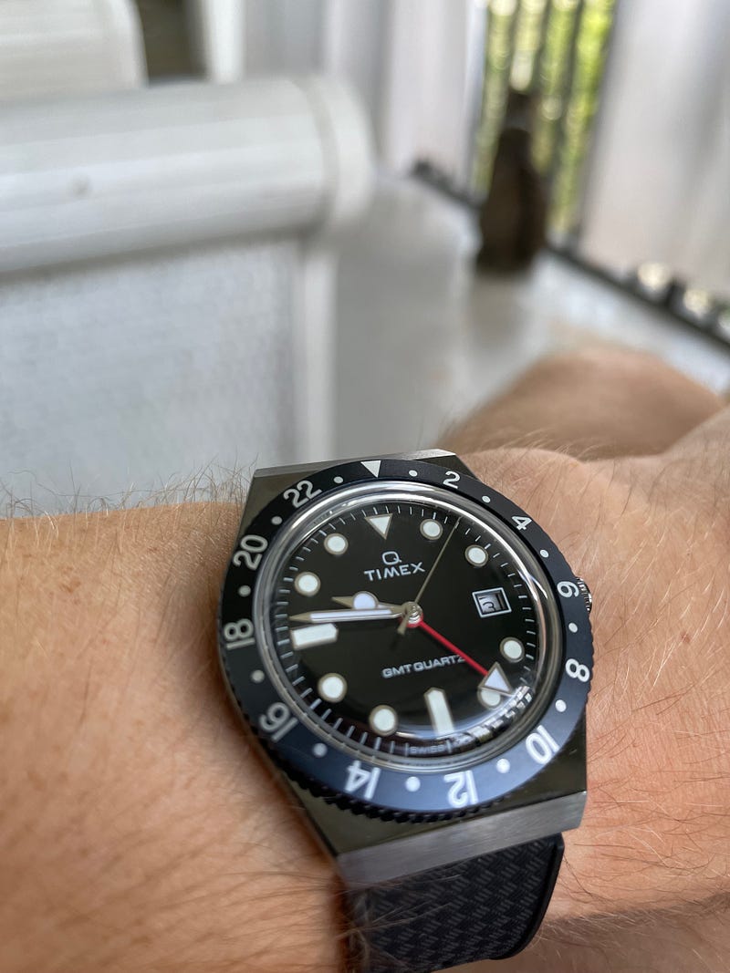 A black Q Timex watch on a wrist.
