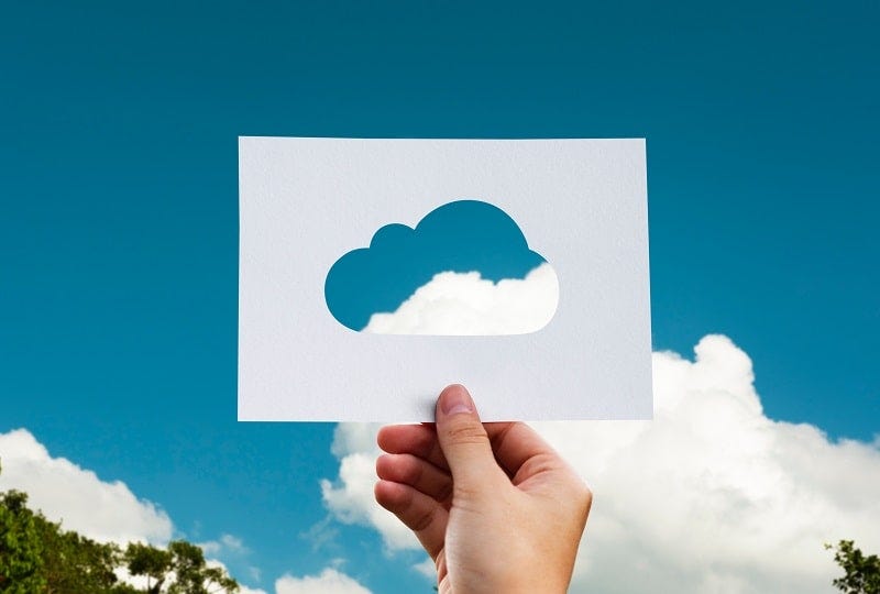 Foto kertas yang berlubang di bagian tengah dengan bentuk awan, serta dihadapkan ke arah langit di mana ada awan sungguhan yang masuk ke dalam lubang kertas tersebut. Mengilustrasikan bahwa artikel ini membahas profesi di bidang cloud computing.