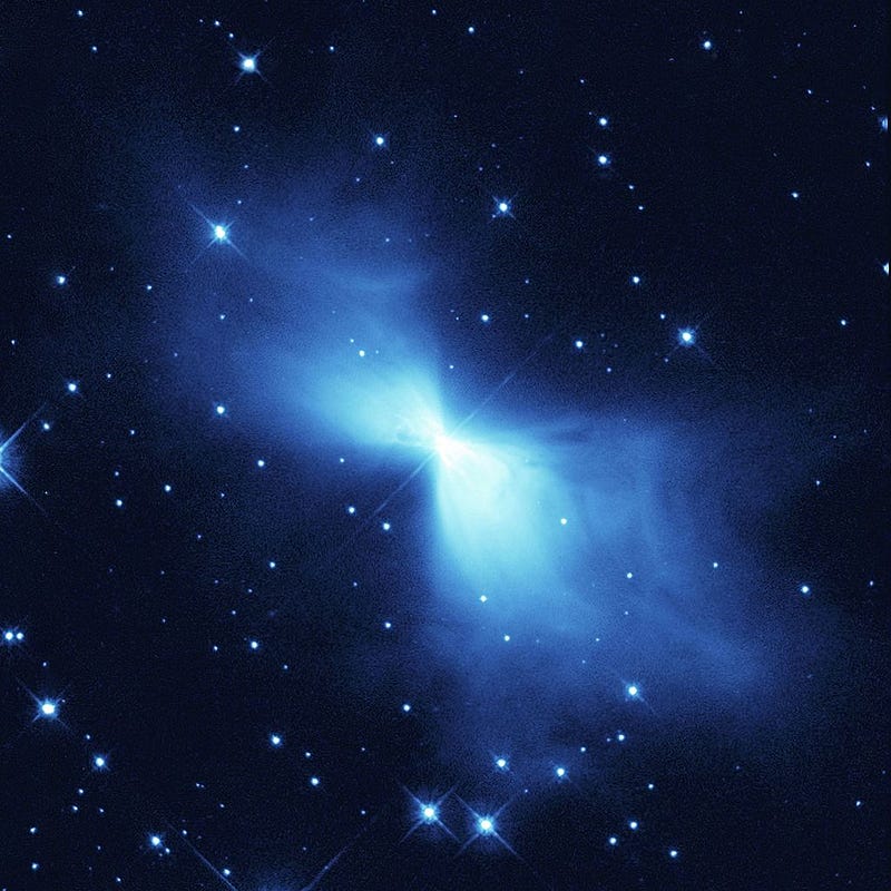 Absolute Zero Investigation: Rapid expansion of gases leaving the Boomerang Nebula, where the lowest temperature outside of laboratories has been observed — 1 Kelvin — It shows a bright light blue coloured hourglass shaped expansion at the centre of a relatively dark part of the sky with many stars in the background.