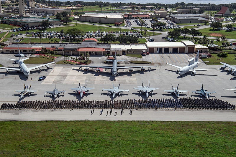 Airplanes and jets lined up behind many people