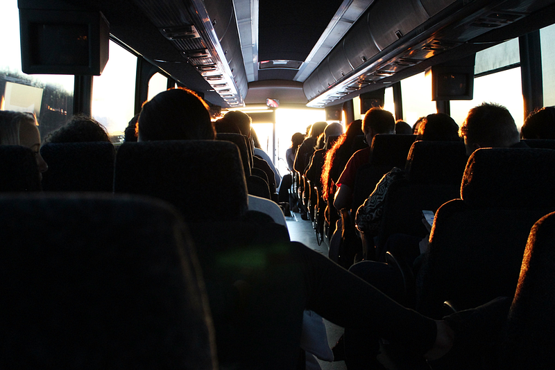 Imagem de diversas pessoas dentro de um ônibus de viagem.