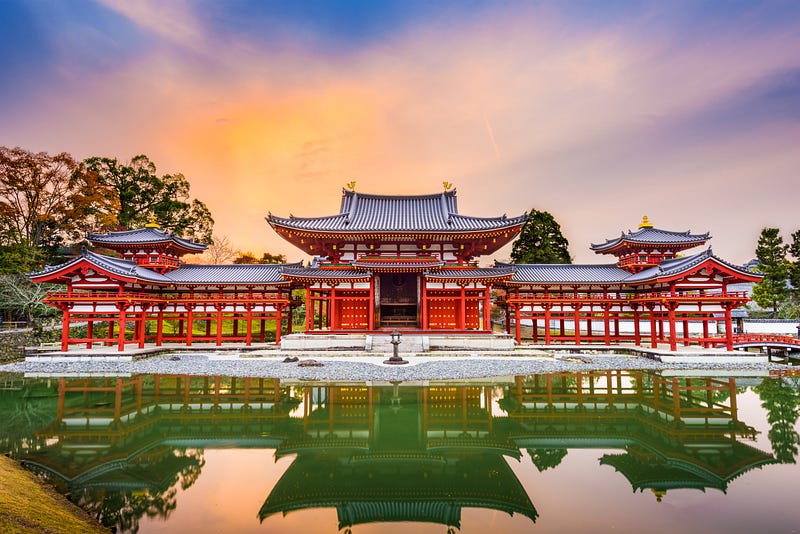 Elaborate, red Buddhist temple reflected in a pond.